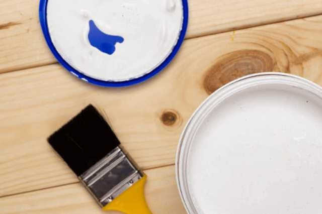 木でできた机にハケと塗料が写っている写真