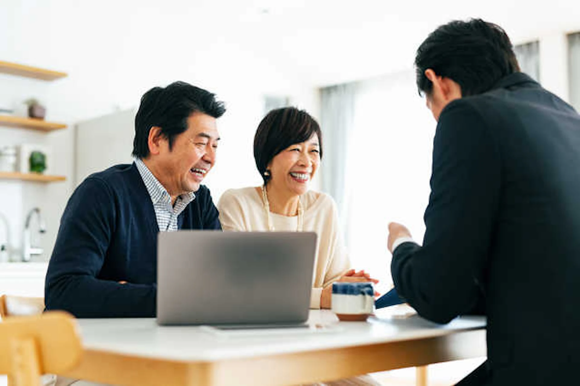 スーツを着た若い男性と、笑顔で話す実年の夫婦