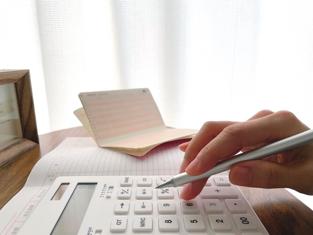 通帳を見ながら電卓を叩く人の様子