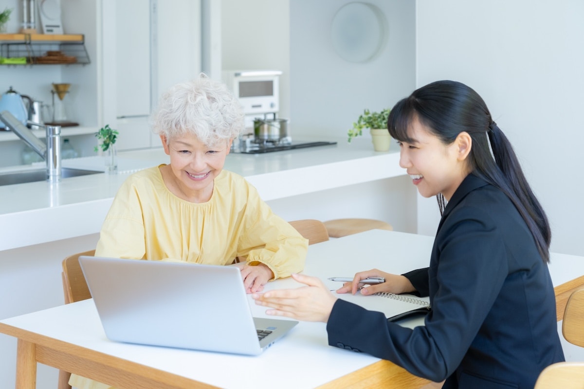 スーツを着た女性と高齢の女性がパソコンを見ながら話している様子