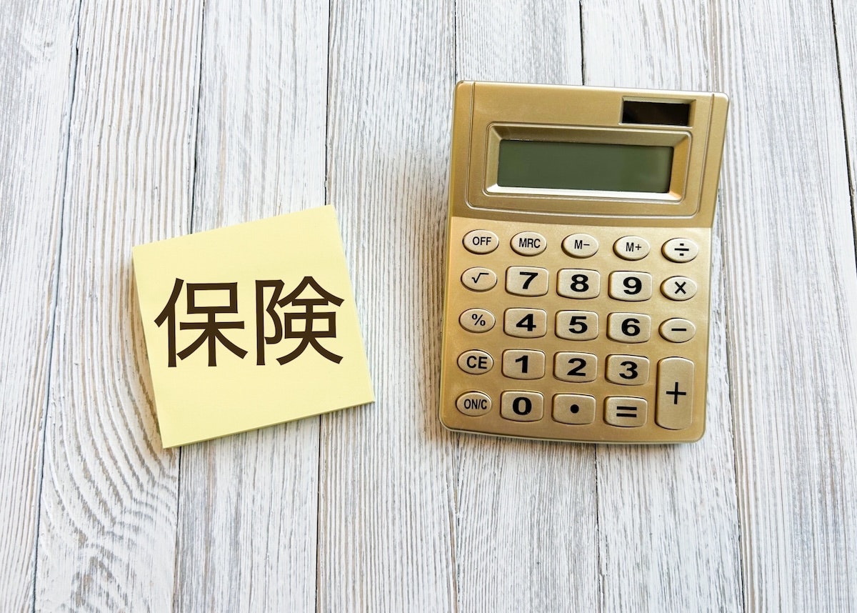 保険と書かれたメモ帳と電卓が並んでいる