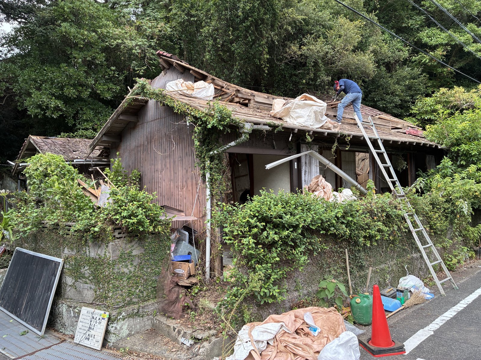 屋根に上がって瓦を手で降ろす