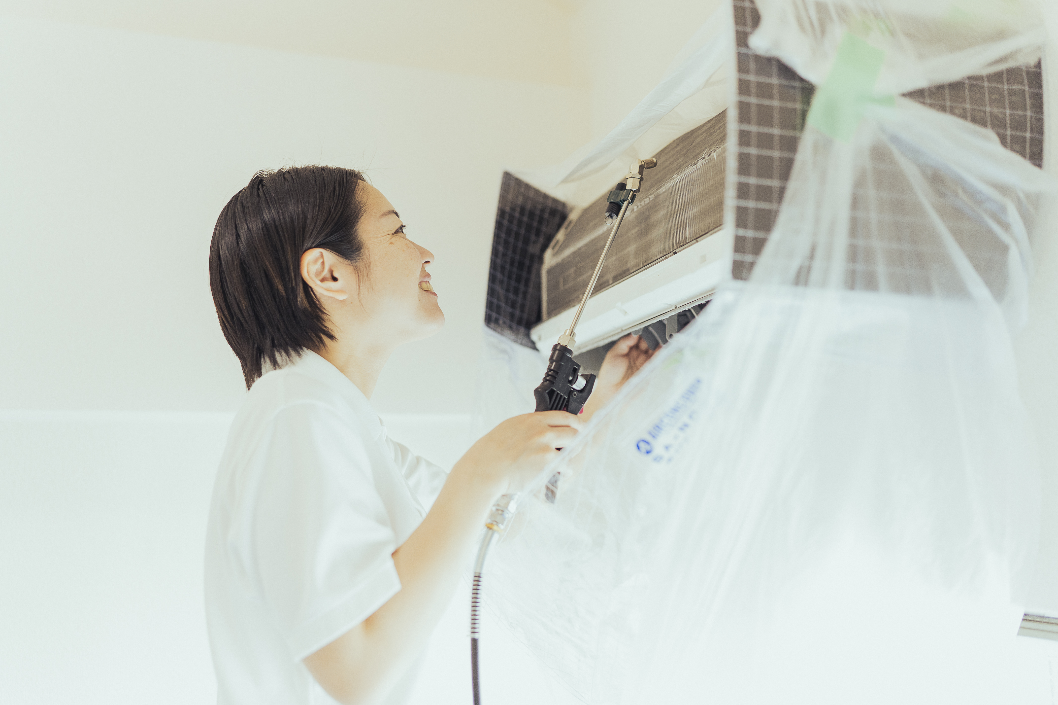 笑顔でエアコンを洗浄する様子