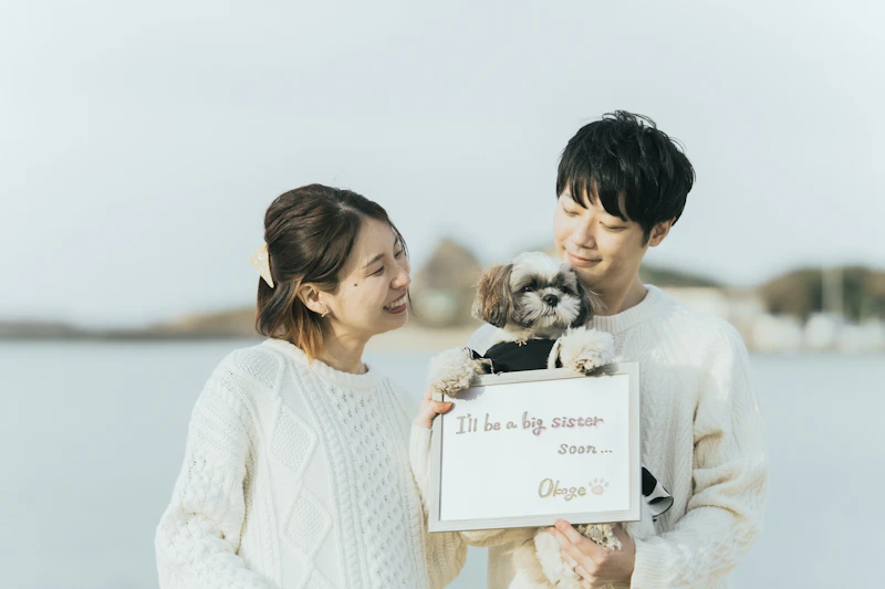 お姉ちゃんになるボードを持つ夫婦と愛犬