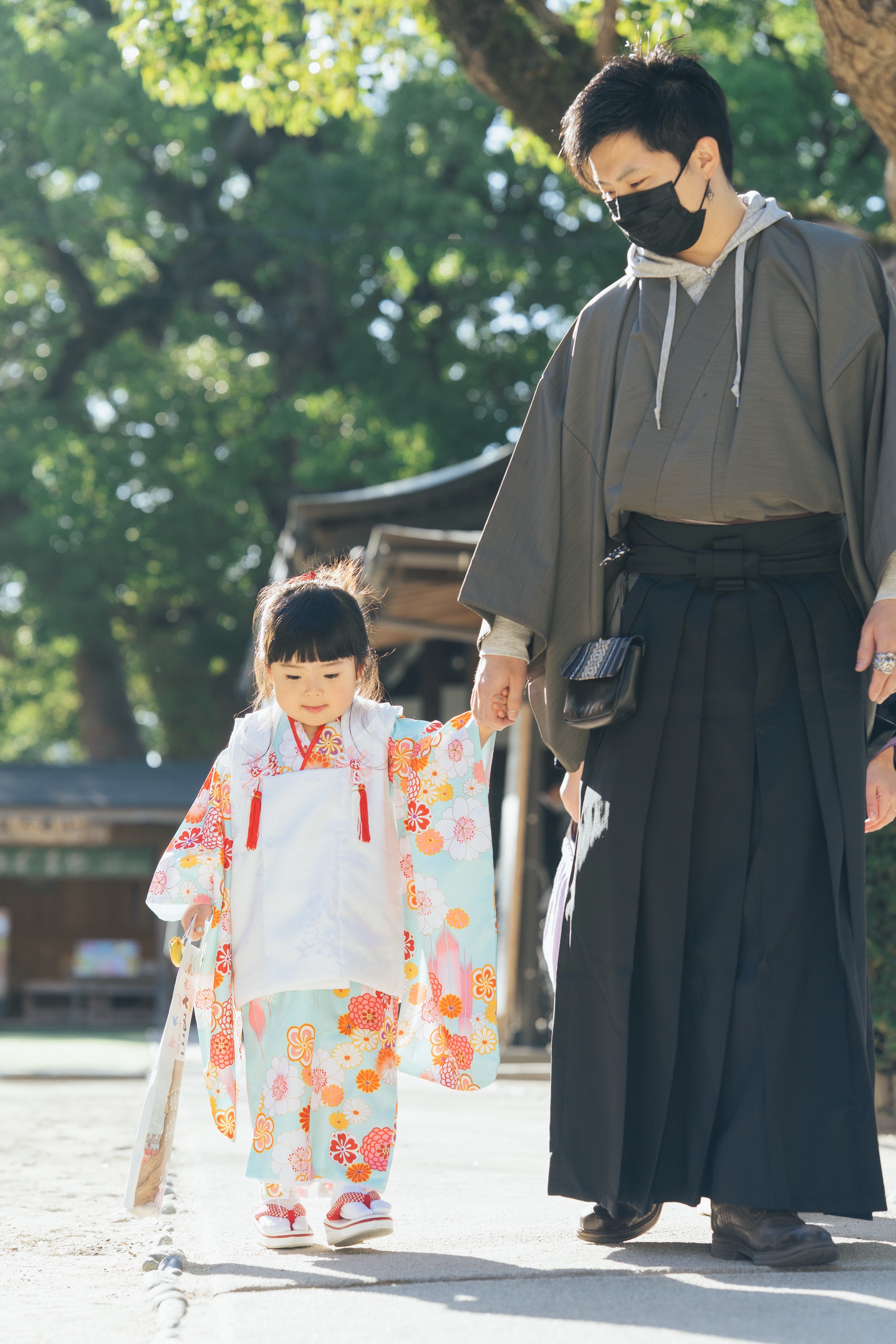 お父さんと手をつないで境内を歩く女の子