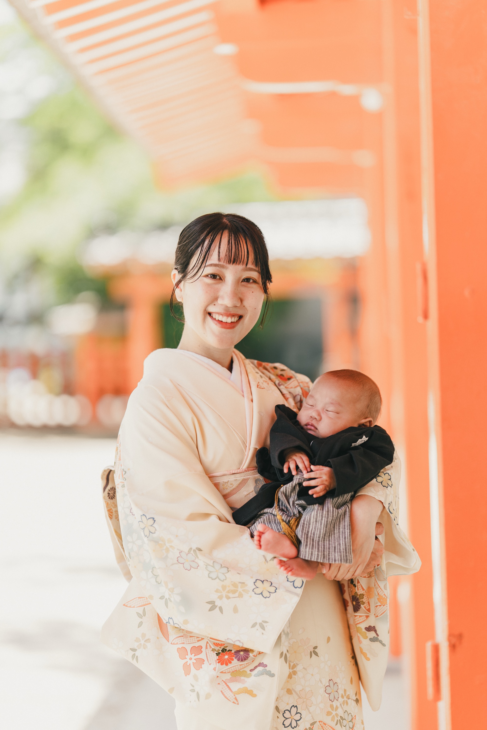朱色の回廊で赤ちゃんを抱いて微笑むお母さん
