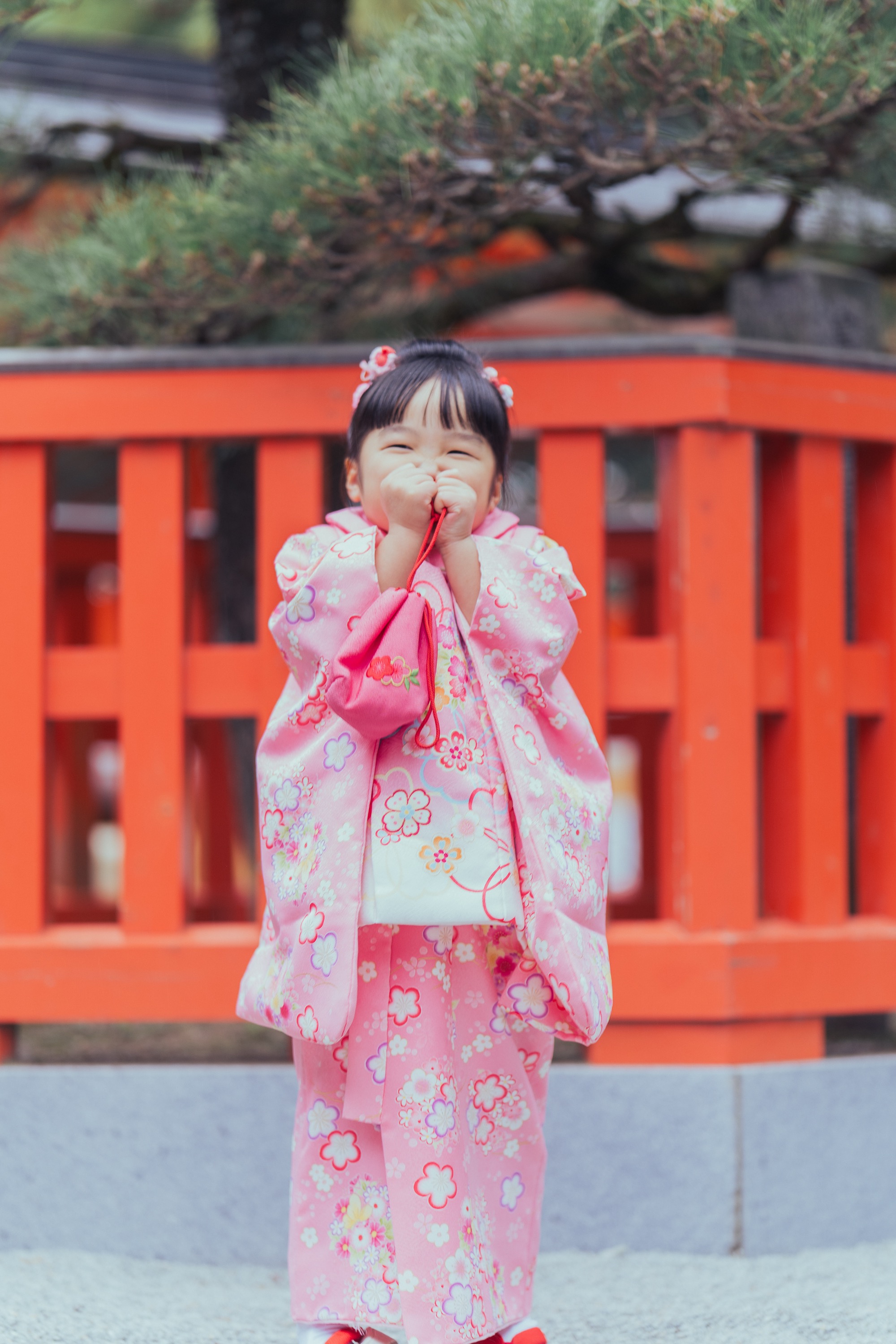 ピンクの着物の妹が巾着を口元に当てて照れ笑い