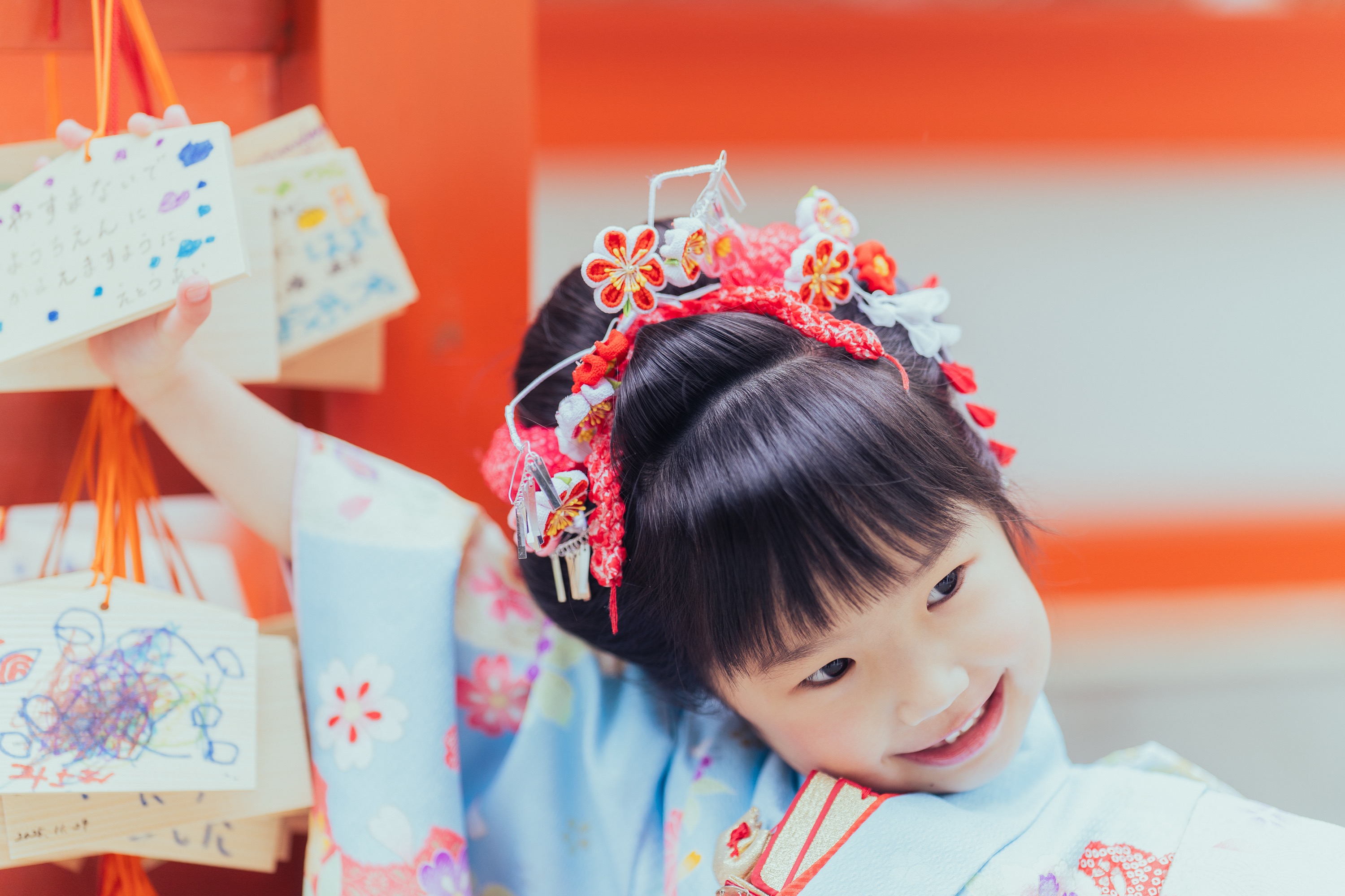 お姉ちゃんが絵馬を手にして首をかしげて微笑んでいる