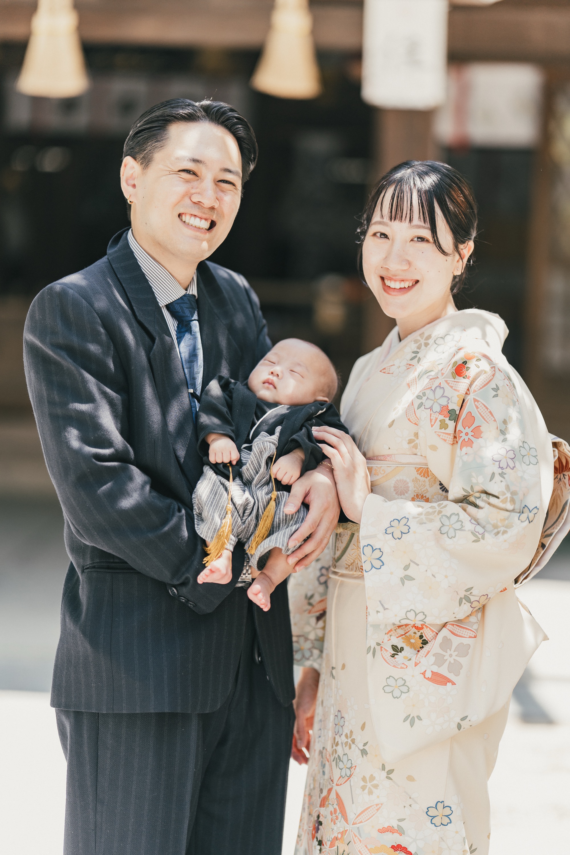社殿の前で赤ちゃんを抱いて笑顔のお父さんとお母さん
