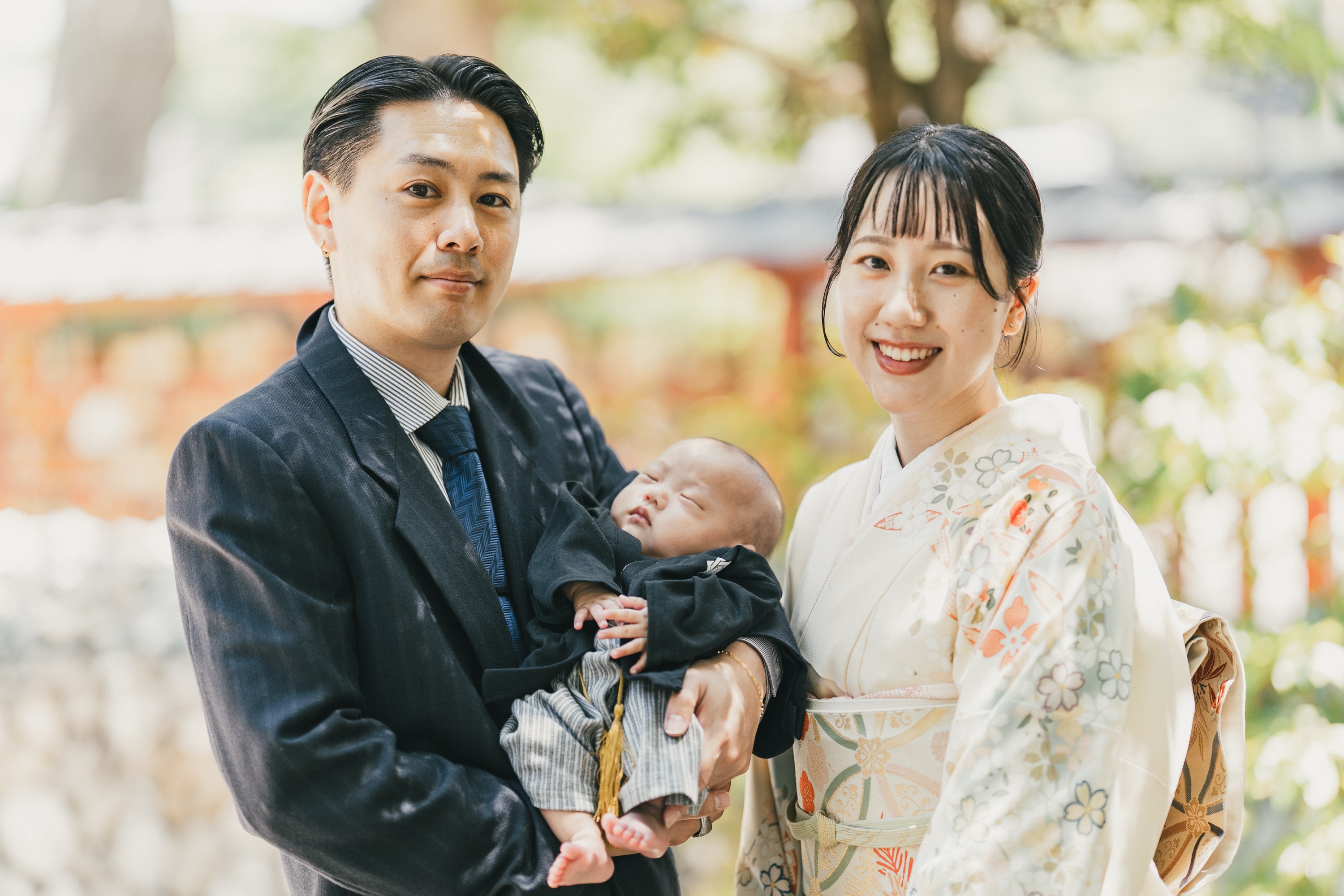 緑の中で赤ちゃんを抱くご両親