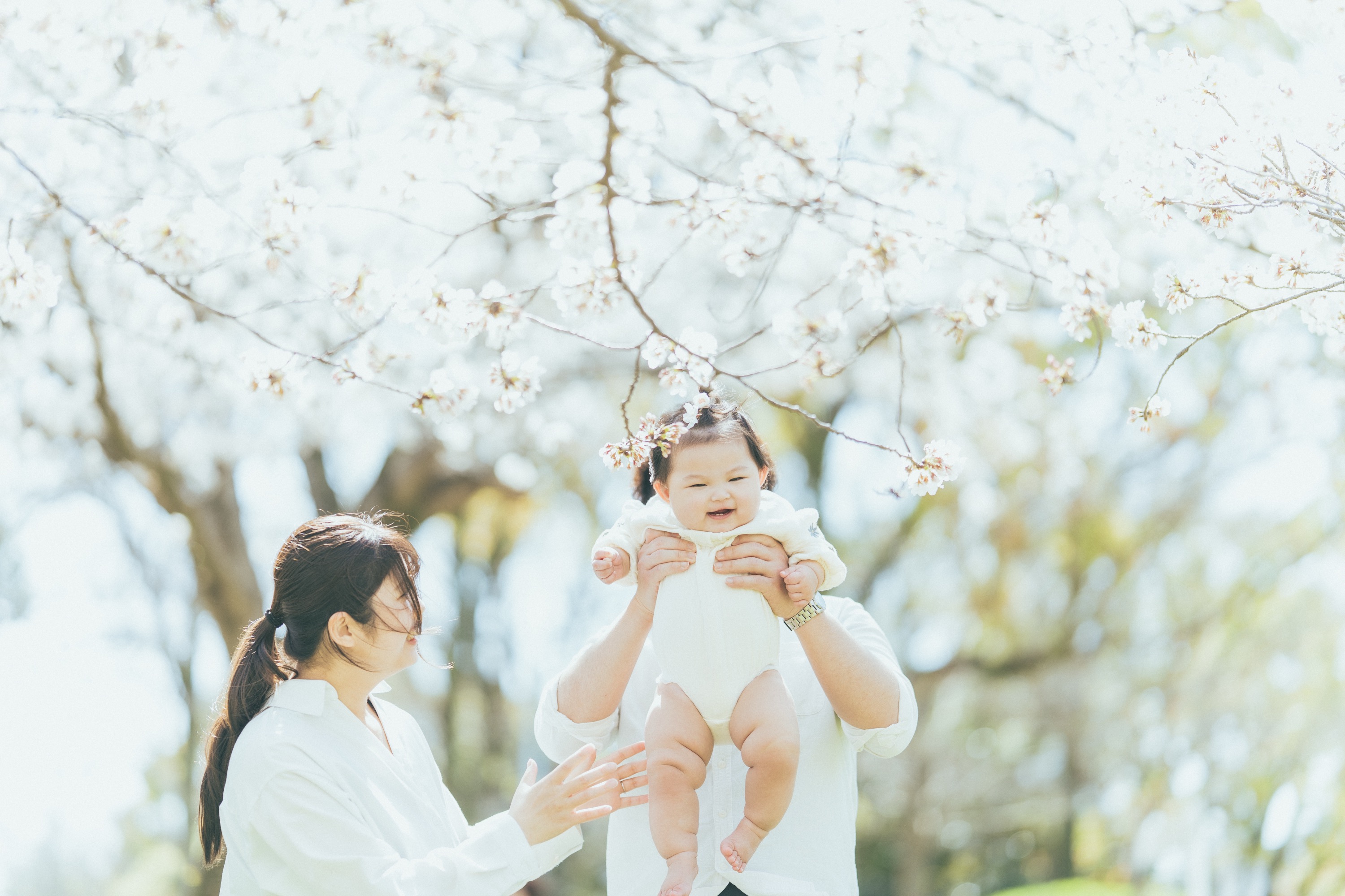 パパに高く抱き上げられて笑う赤ちゃん