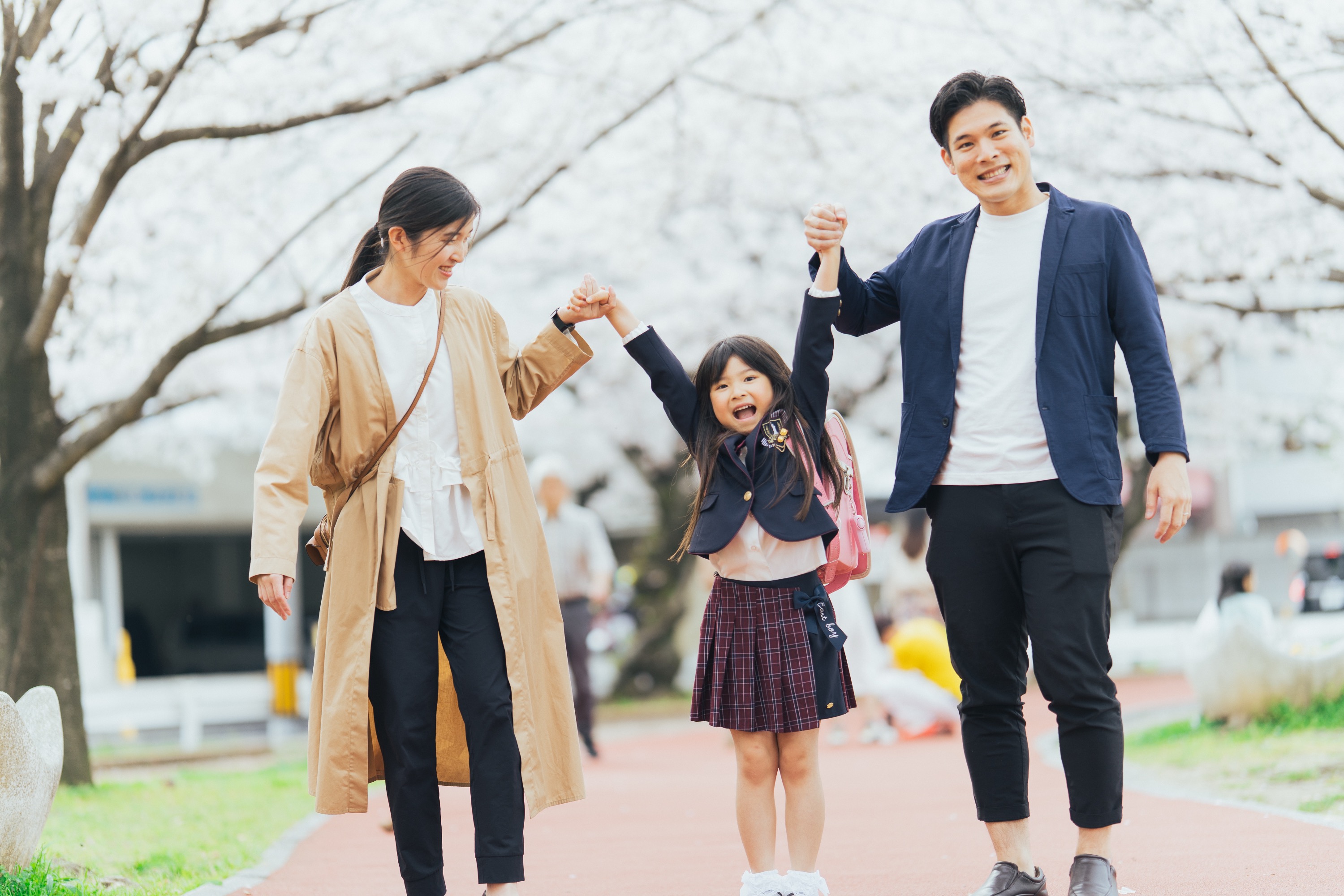 桜並木を家族3人で手をつないで歩く
