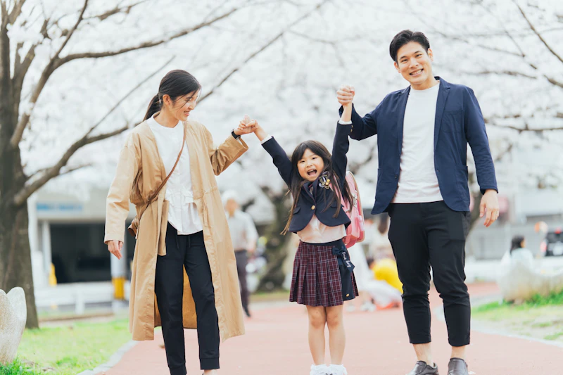 桜並木を家族3人で手をつないで歩く