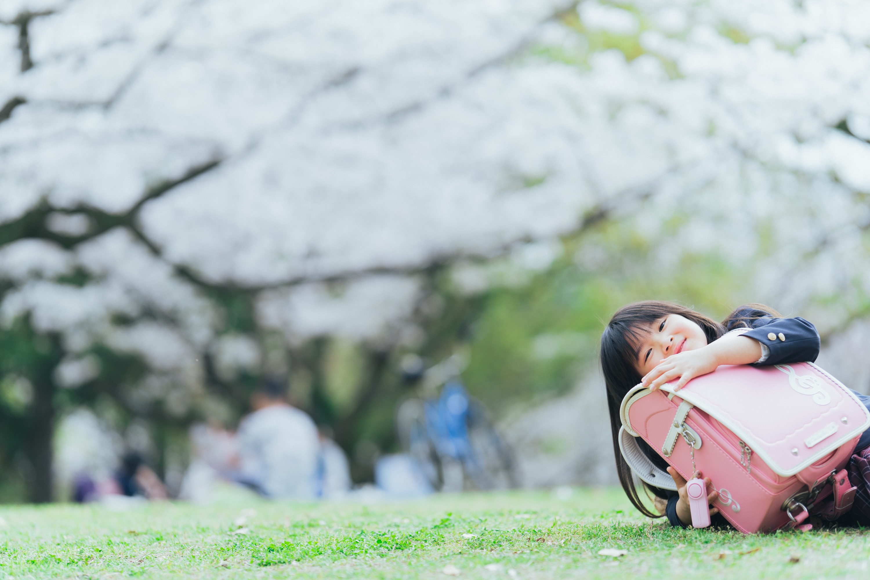 芝生の上でランドセルに寄りかかる女の子