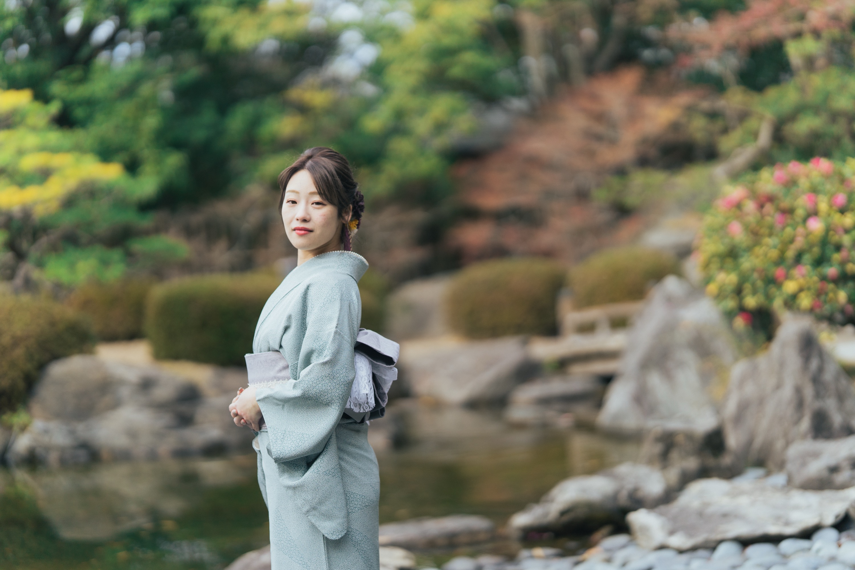 日本庭園の池のほとりに立つ着物姿の女性