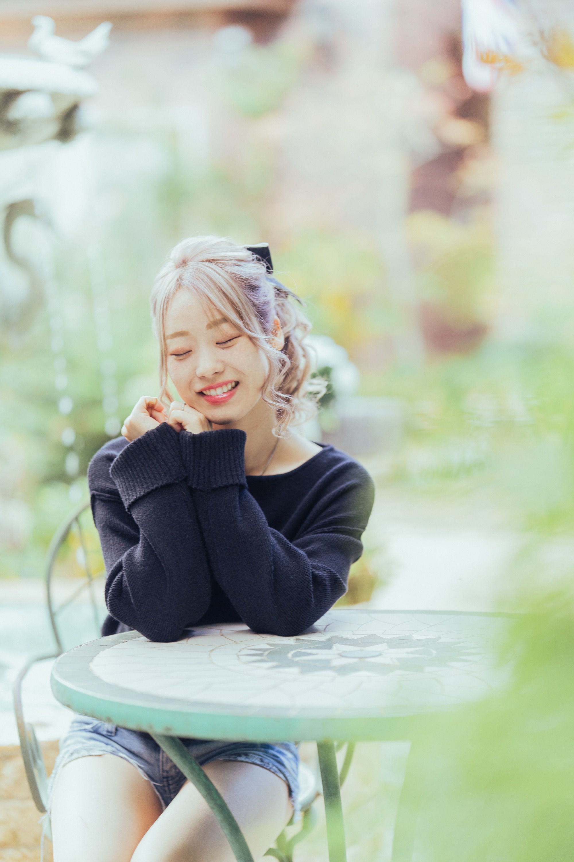 ガーデンテーブルで目を閉じて笑う女性