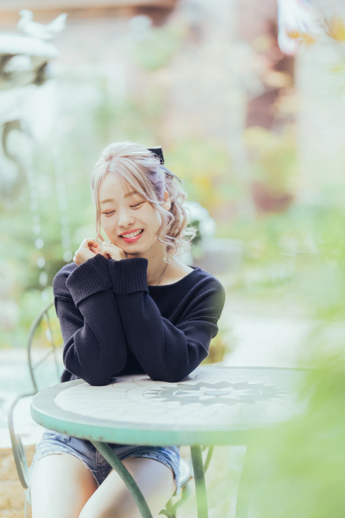 ガーデンテーブルで目を閉じて笑う女性