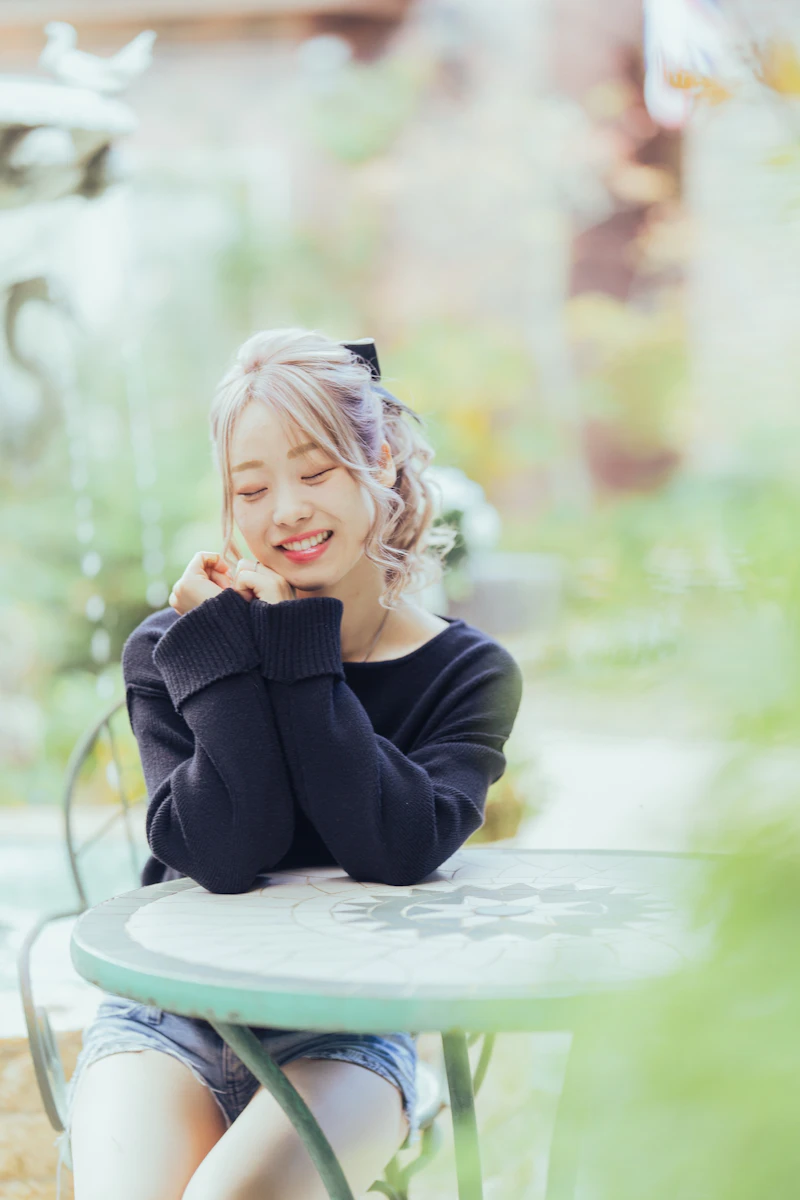 ガーデンテーブルで目を閉じて笑う女性