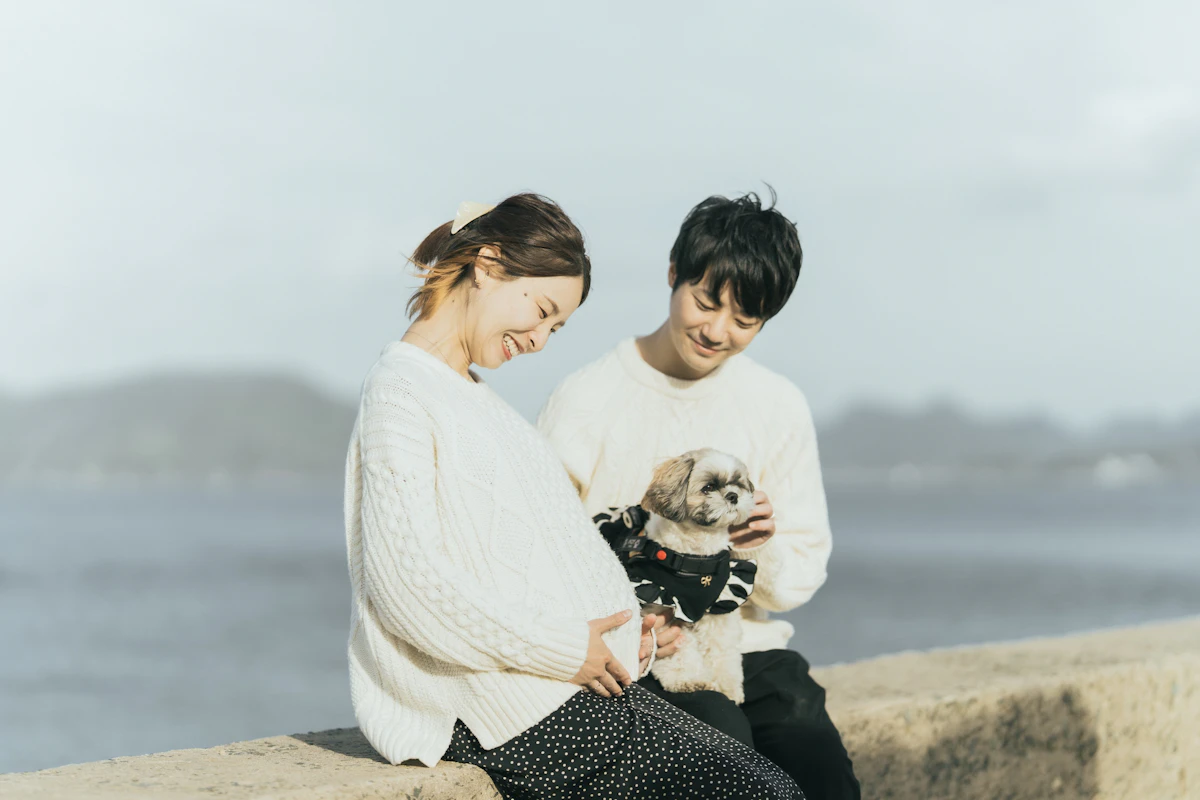 海辺の堤防に座り愛犬を抱える夫婦