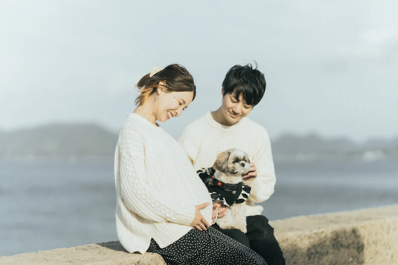 海辺の堤防に座り愛犬を抱える夫婦