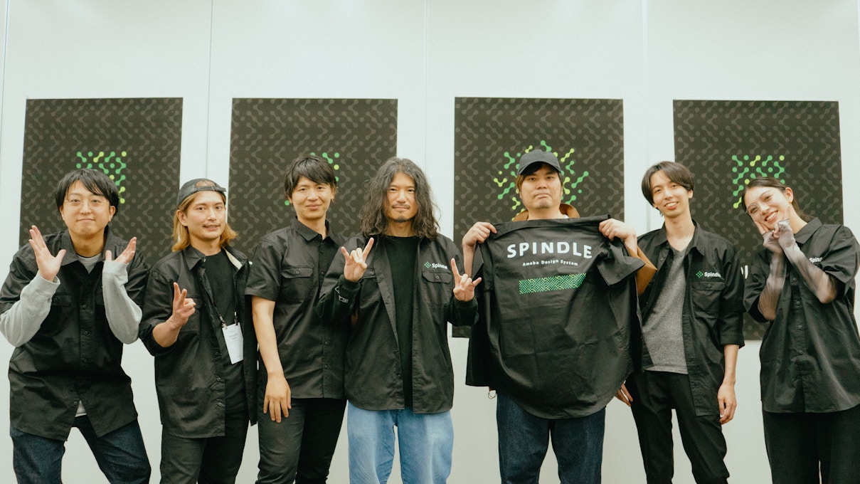 Spindle運営メンバーたちが一列に並び、ロゴ入りの黒いユニフォームを着てポーズをとっている。