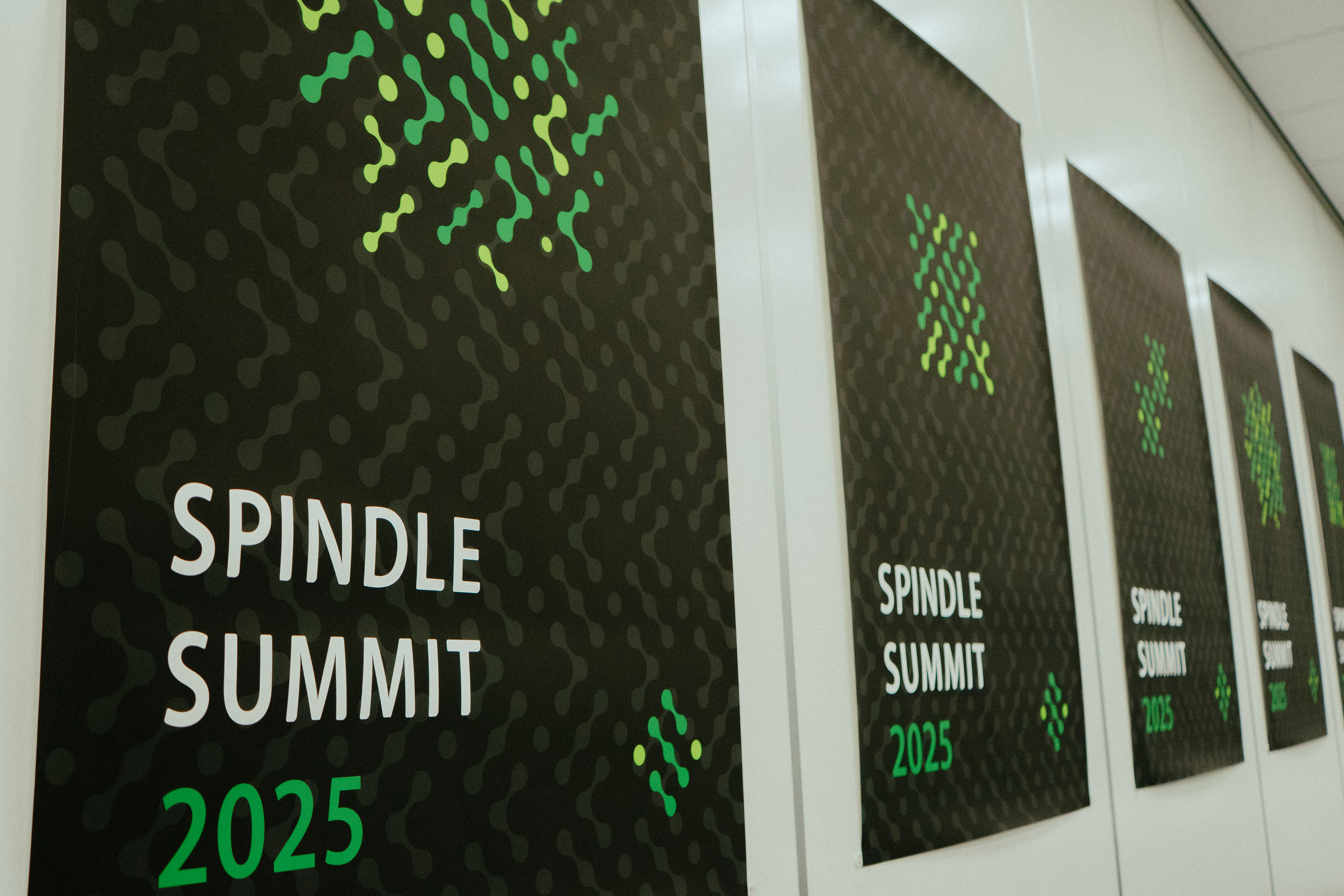 会場の壁に並べられた「Spindle SUMMIT 2025」の公式バナー。黒地にグリーンのドット模様が印象的で、統一感のあるブランディングが際立つ。