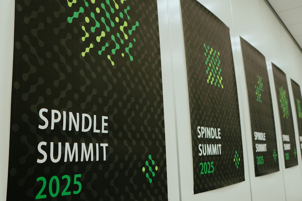 会場の壁に並べられた「Spindle SUMMIT 2025」の公式バナー。黒地にグリーンのドット模様が印象的で、統一感のあるブランディングが際立つ。
