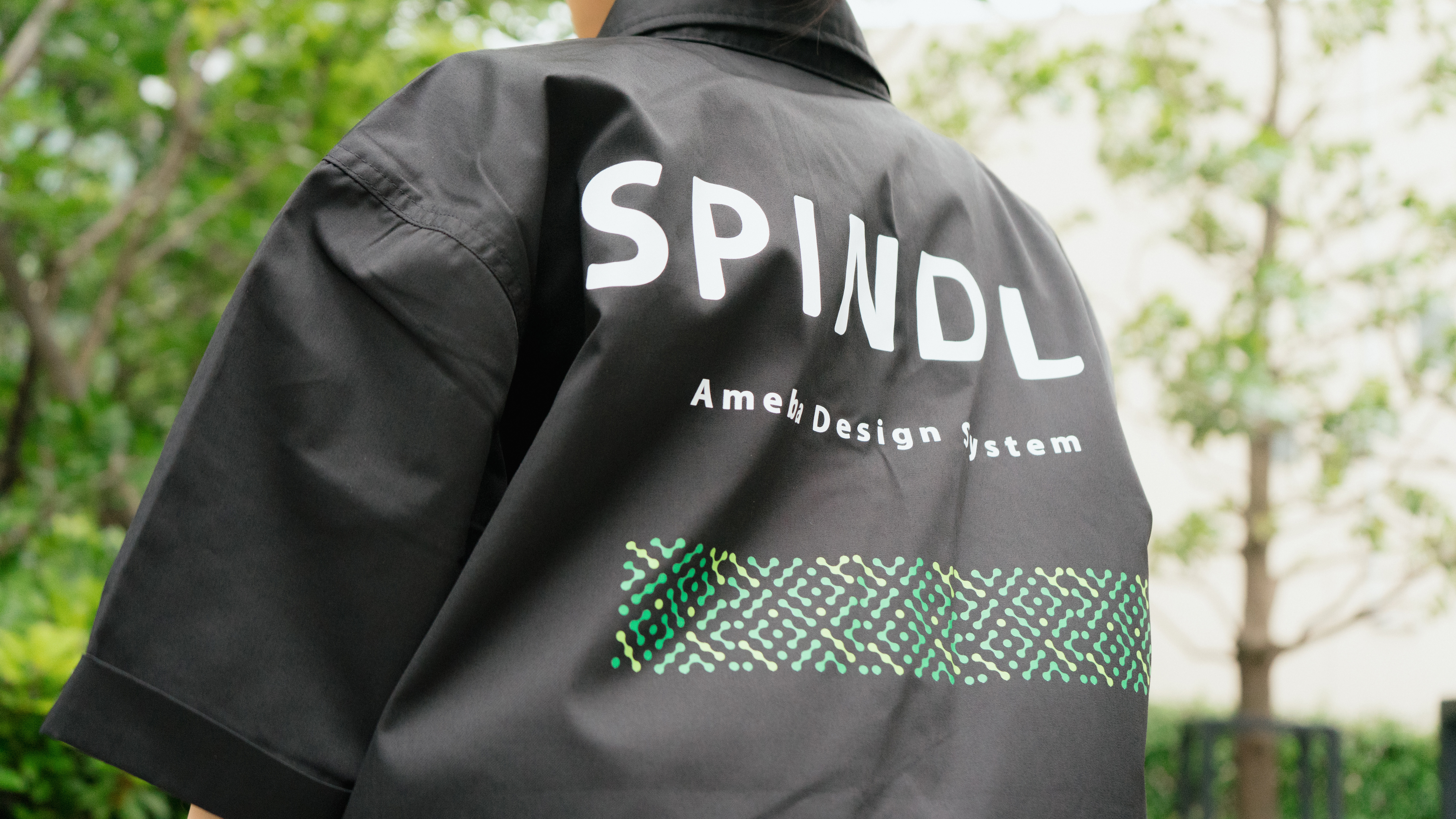 Spindleのワークシャツ背面にあしらわれたロゴと「Ameba Design System」の文字が大きく写されたクローズアップショット。ブランドの力強さを感じさせる構図。