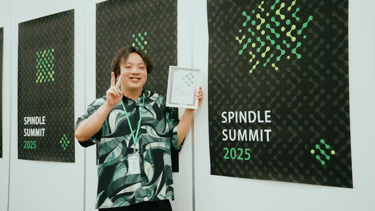 Spindle SUMMIT 2025の表彰式にて、受賞者が賞状を手に笑顔でピースサインをしている様子。
