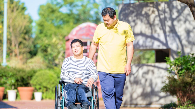 ご利用者と外で散歩をする障害者支援施設の介護職員の様子
