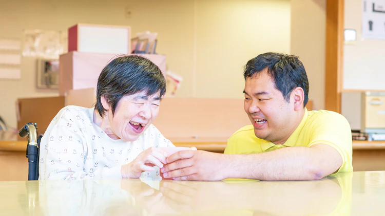 ご利用者と笑顔で話す障害者支援施設の介護職員の様子