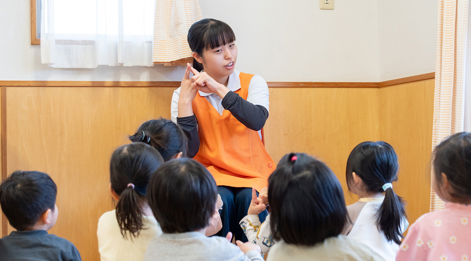 子どもたちと手遊びをする女性保育士の様子