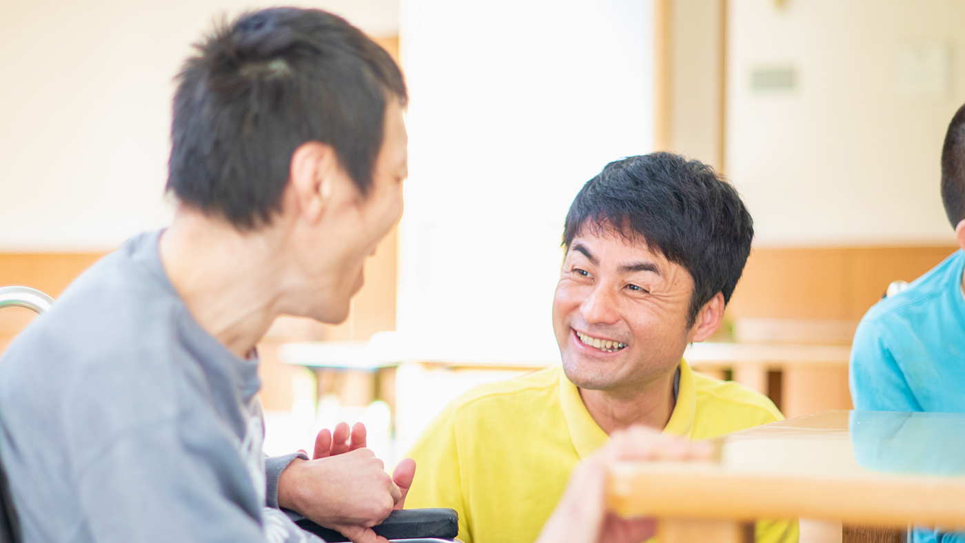 ご利用者の男性と笑顔で会話する介護職員の男性