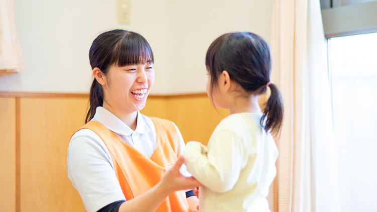 子どもと向かい合い笑顔で話す女性保育士