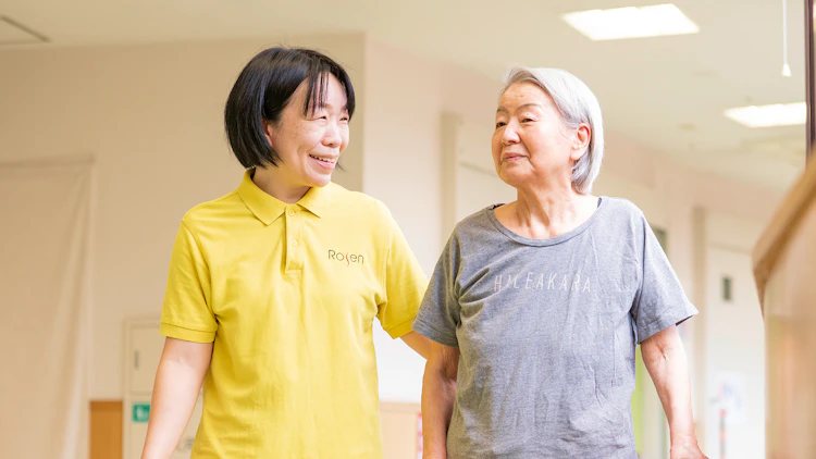 入居者の女性の歩行を介助する介護職員の女性