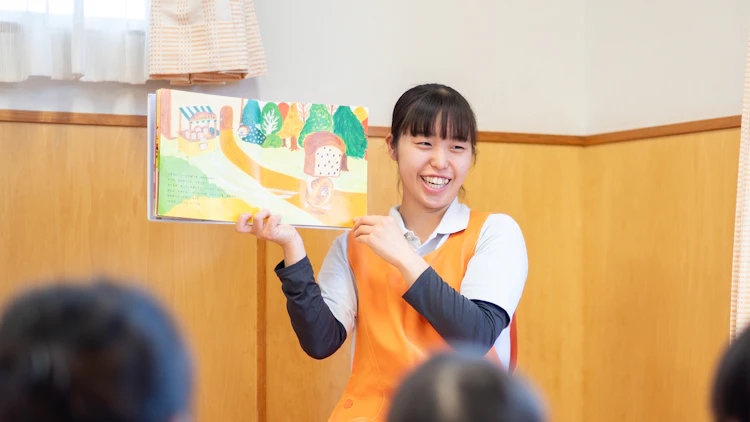 子どもたちへ絵本を読む女性保育士の様子