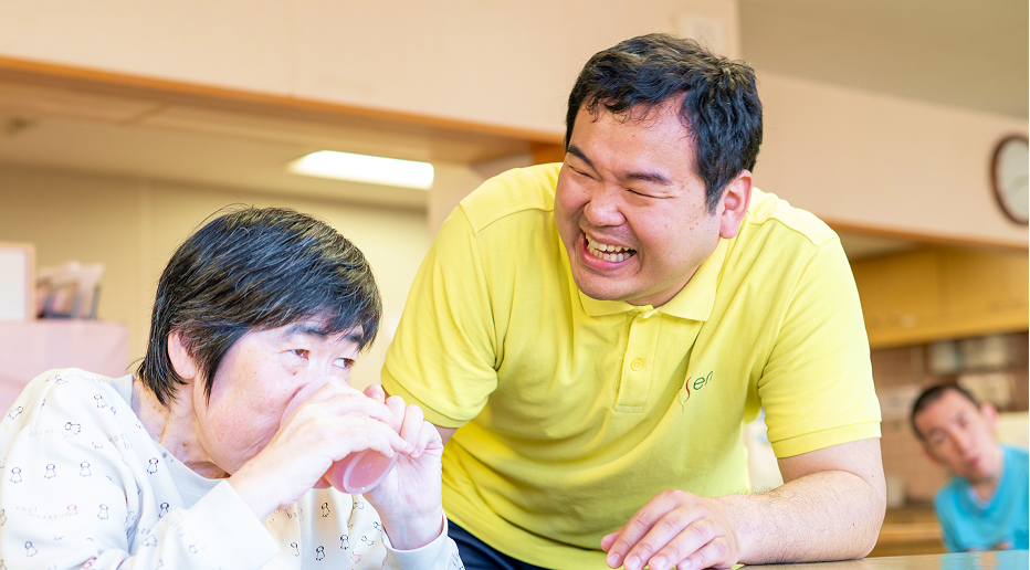 ご利用者と笑顔で話す障害者支援施設の介護職員の写真