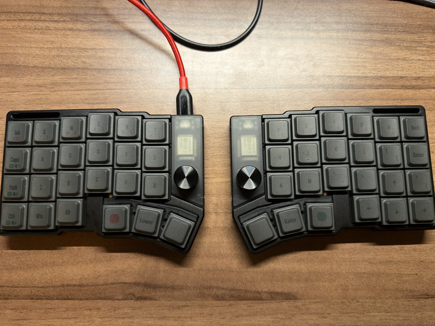 机の上の cornix LP。左右セパレートの 2 ピース構成で、各ハーフにロータリーノブと小さな OLED を備える