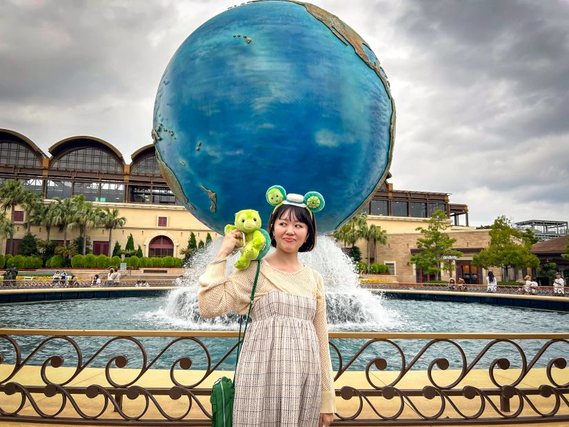 会社から支給された軍資金で買い物を楽しむ女性メンバー。ディズニーキャラクター オル・メルのぬいぐるみを方に乗せている。頭には同じくオル・メルのカチューシャも身につけている。