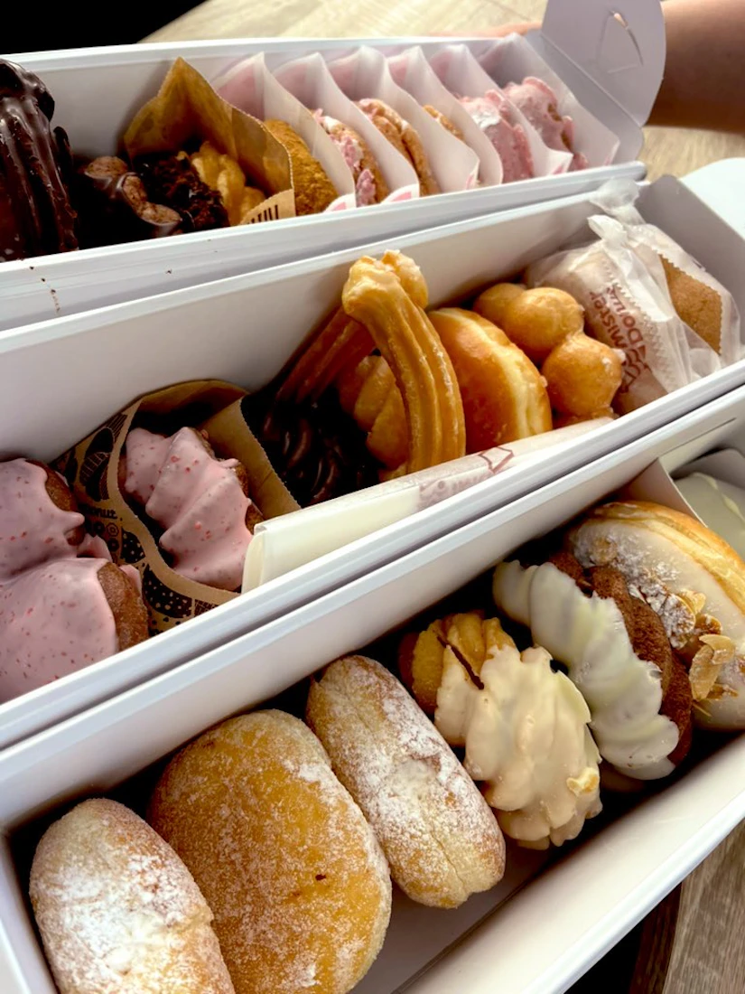 3つの箱いっぱいに入ったミスタードーナツのドーナツ。エンゼルクリーム、ポン・デ・リング、チュロス、などなど。