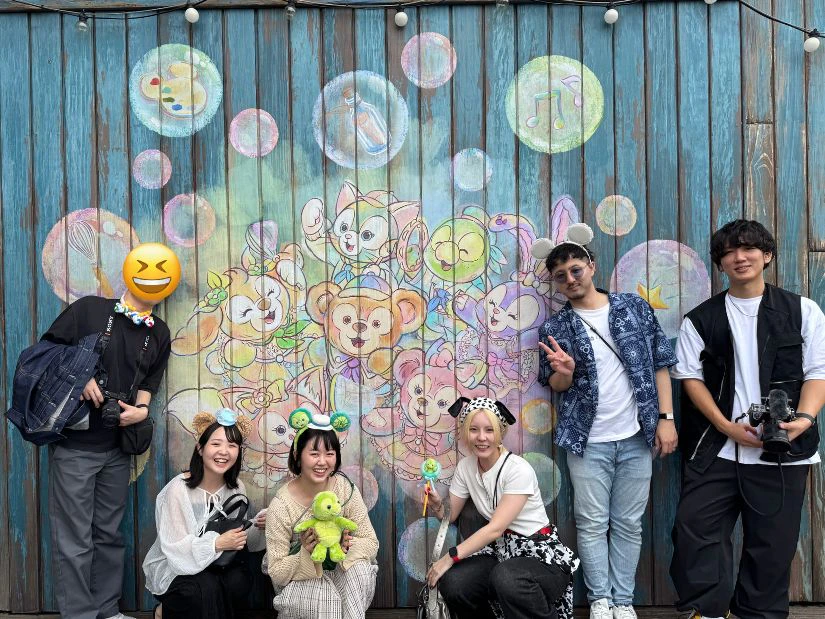 ディズニーの人気キャラクター ダッフィーアンドフレンズのデコレーションの前で記念撮影をするメンバーの写真。