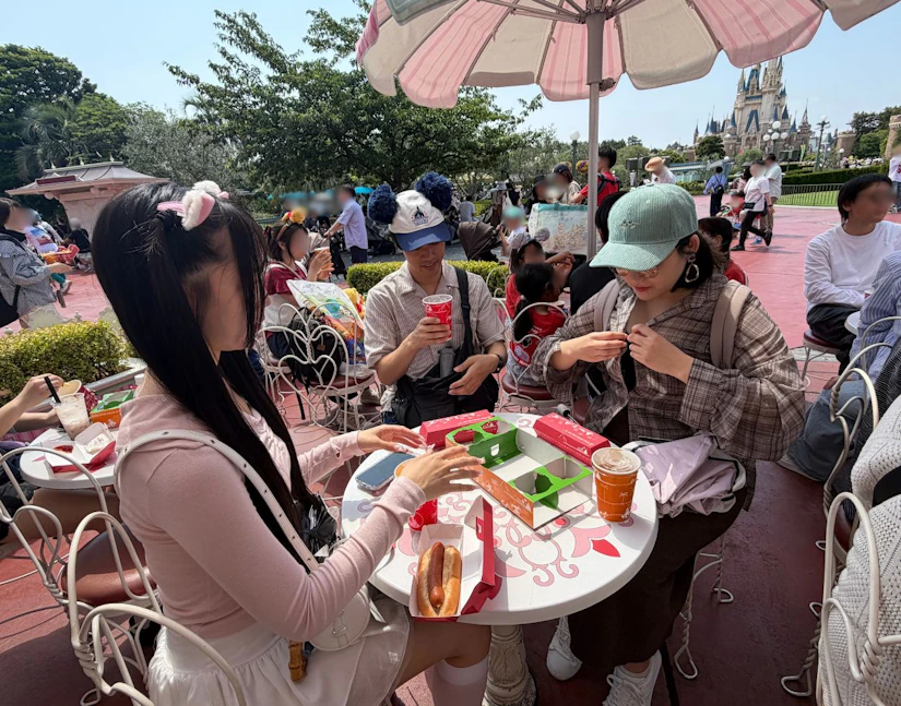 ディズニーランドでホットドックなどの朝食を楽しむ様子。