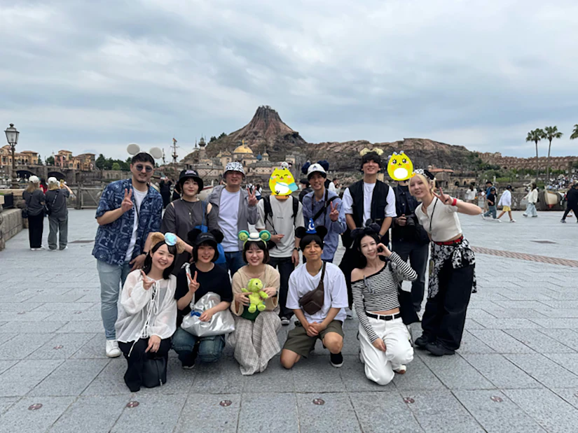 ノベルティ社員がディズニーシーのプロメテウス火山の前で並んでポーズをとっている。集合写真。