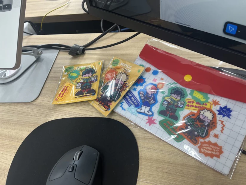 パソコンデスク。「僕のヒーローアカデミア」のグッズ。アクリルキーホルダーと、ビニールのポーチにデフォルメキャラクターが描かれている。