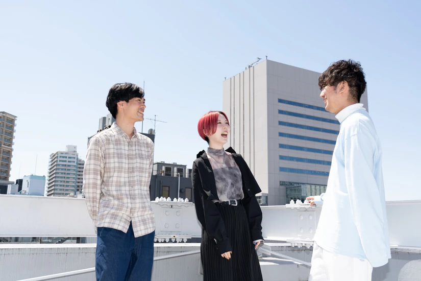 青空の下で笑顔で会話をするノベルティスタッフの写真