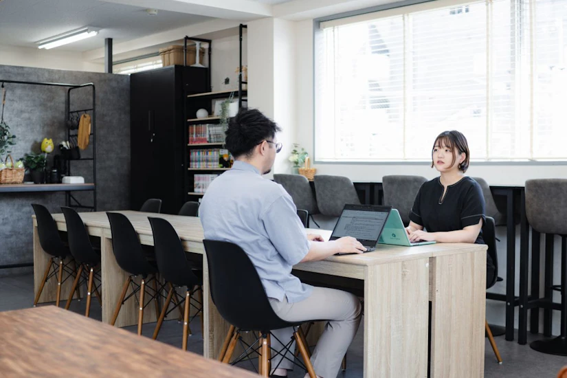 テーブルで向かい合って座り話し合う人物。