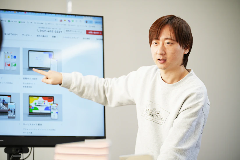男性がモニターを指して説明をしている様子。