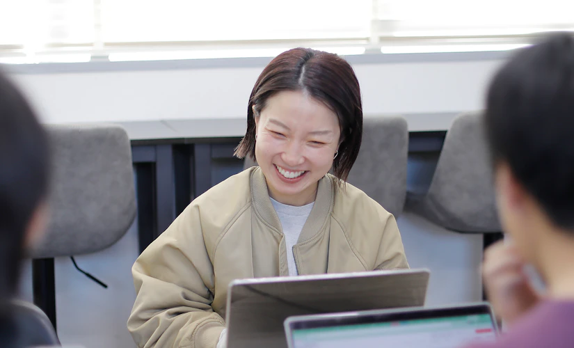 PCを使いながら社内の人と話す写真