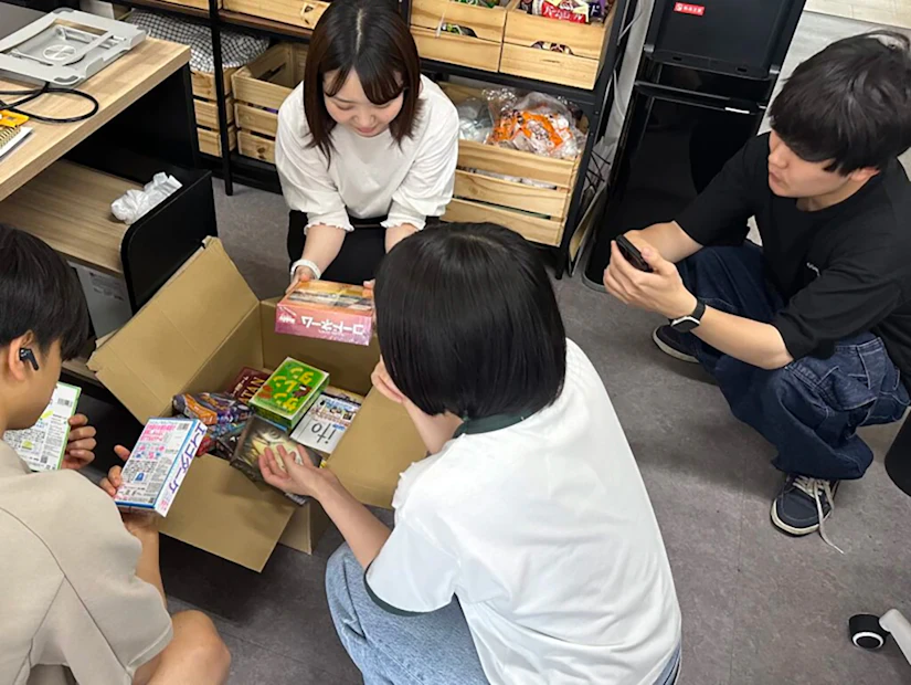 ノベルティ社員が届いたばかりのボードゲームをダンボールから取り出している。