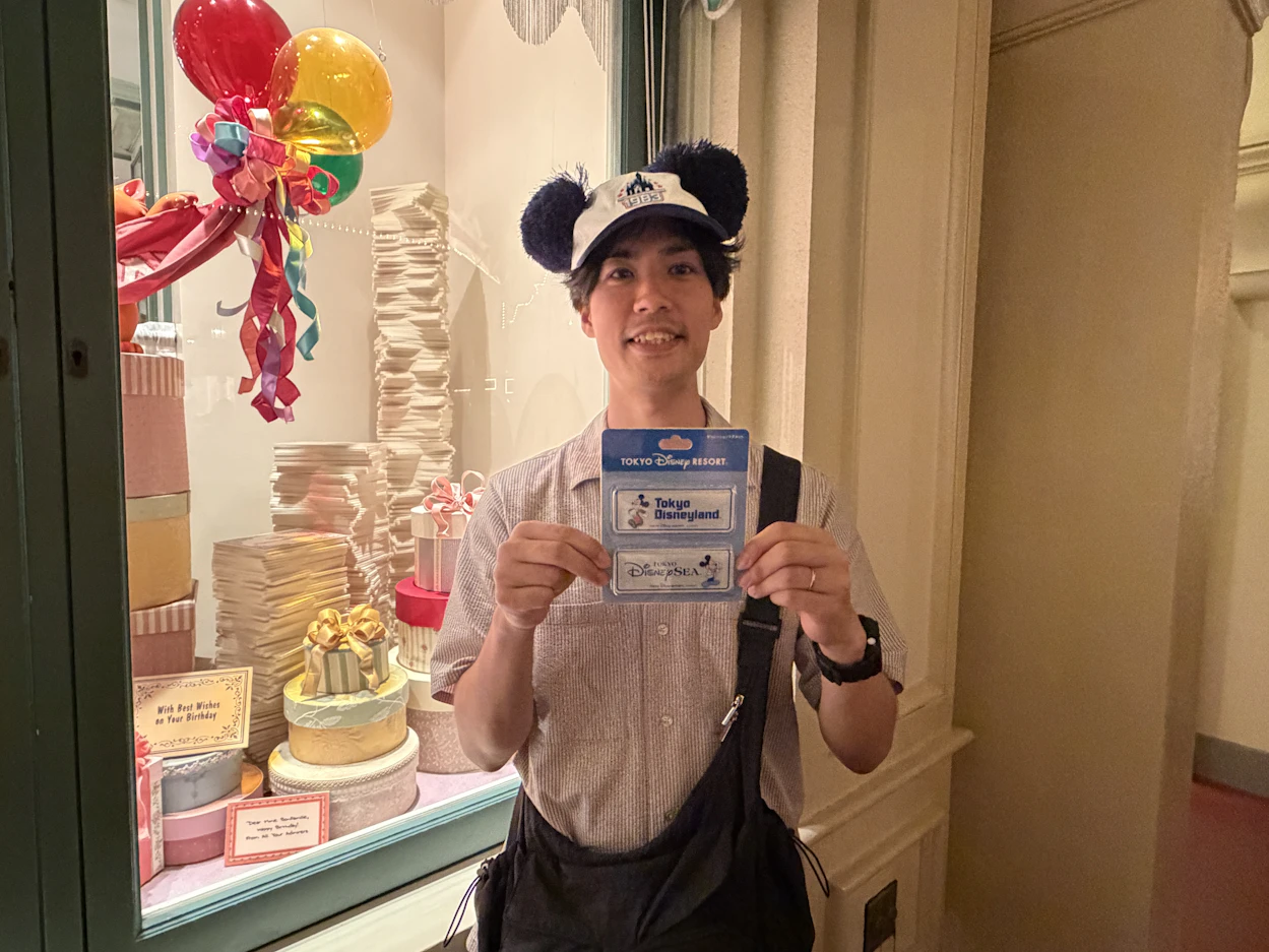 お土産を両手で持ち笑顔の男性社員の写真。